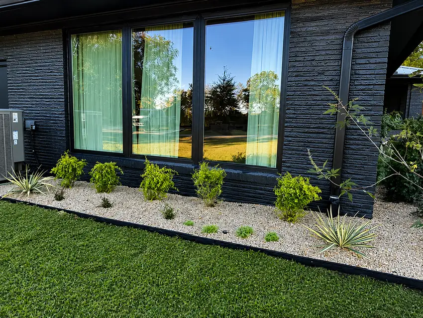 Clean gravel and grass border along a modern glass facade — Landscape Design & Maintenance