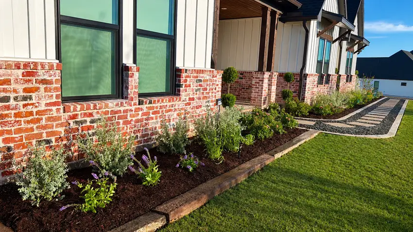 Foundation bed and lawn edge along a brick and metal building — Landscape Design & Maintenance
